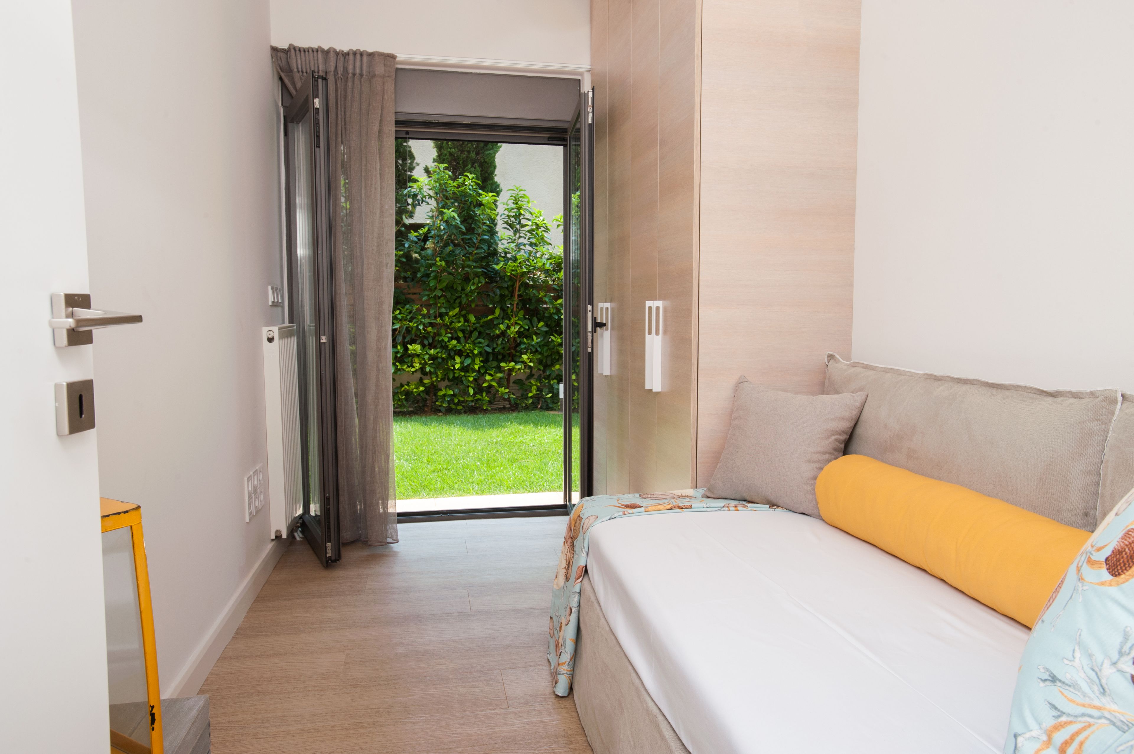 Une chambre avec un lit, une porte-fenêtre coulissante donnant sur un jardin et une petite table.