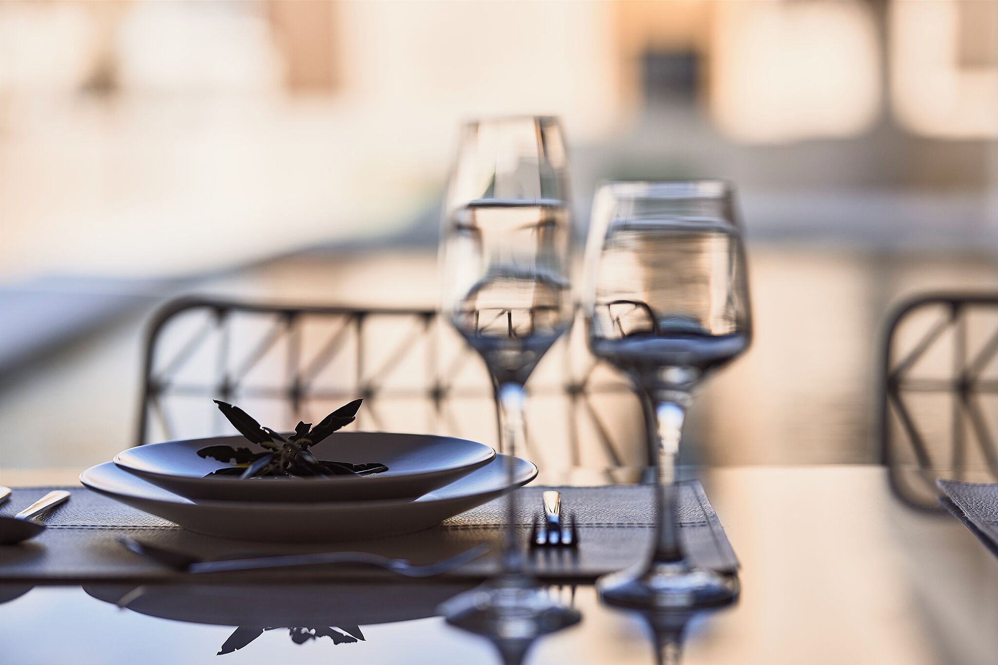 A dining table with a plate of food, two wine glasses, and a fork.