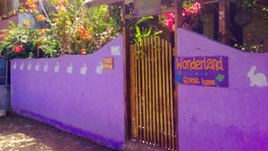 Un edificio de paredes moradas con un letrero que dice "Wonderland Guest House" y una reja.