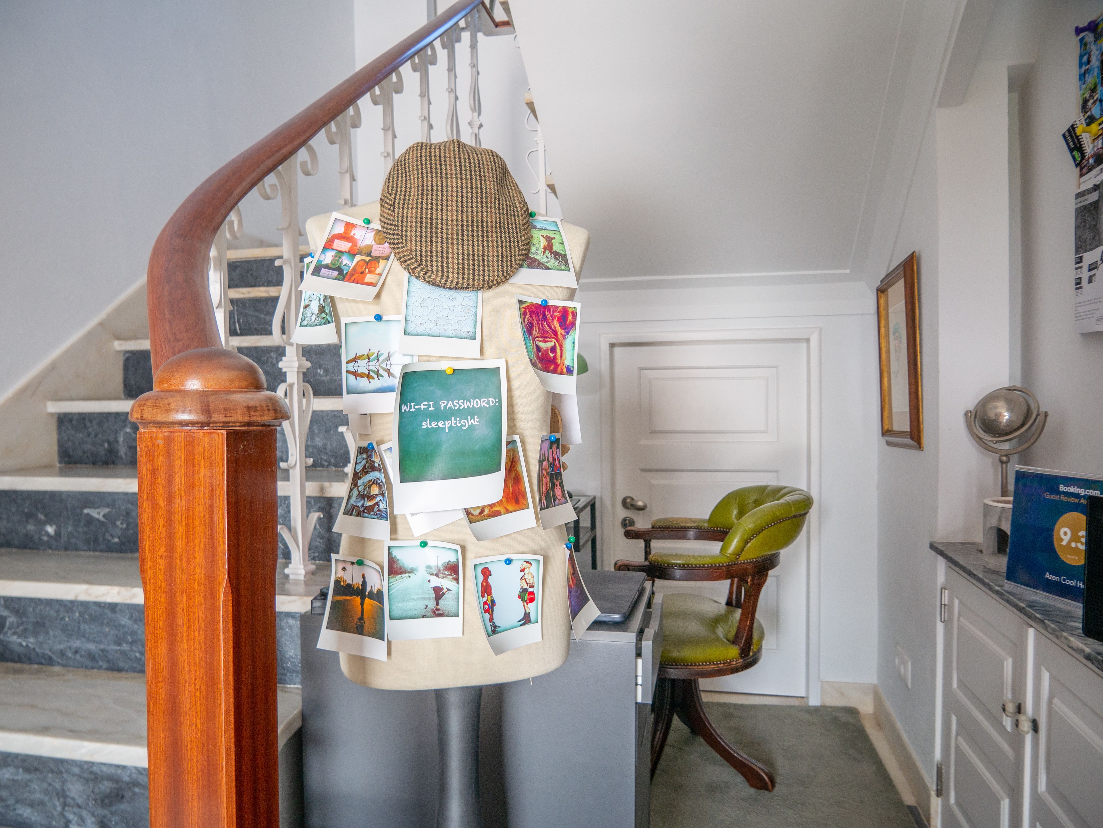 A staircase with a wooden handrail, a wall decorated with various photographs and a sign with a Wi-Fi password.