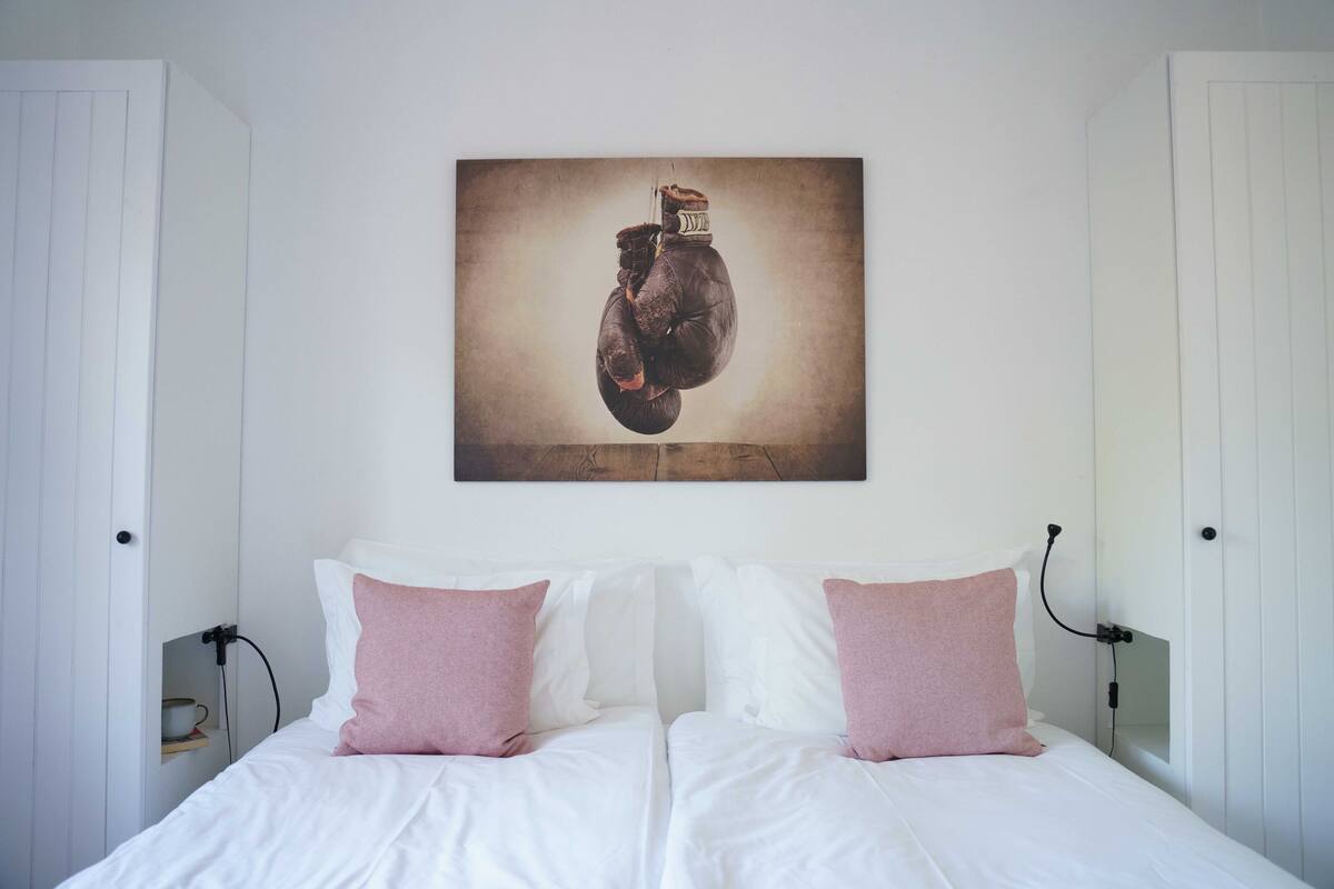A bedroom with a bed, white bedding, and two pink pillows.