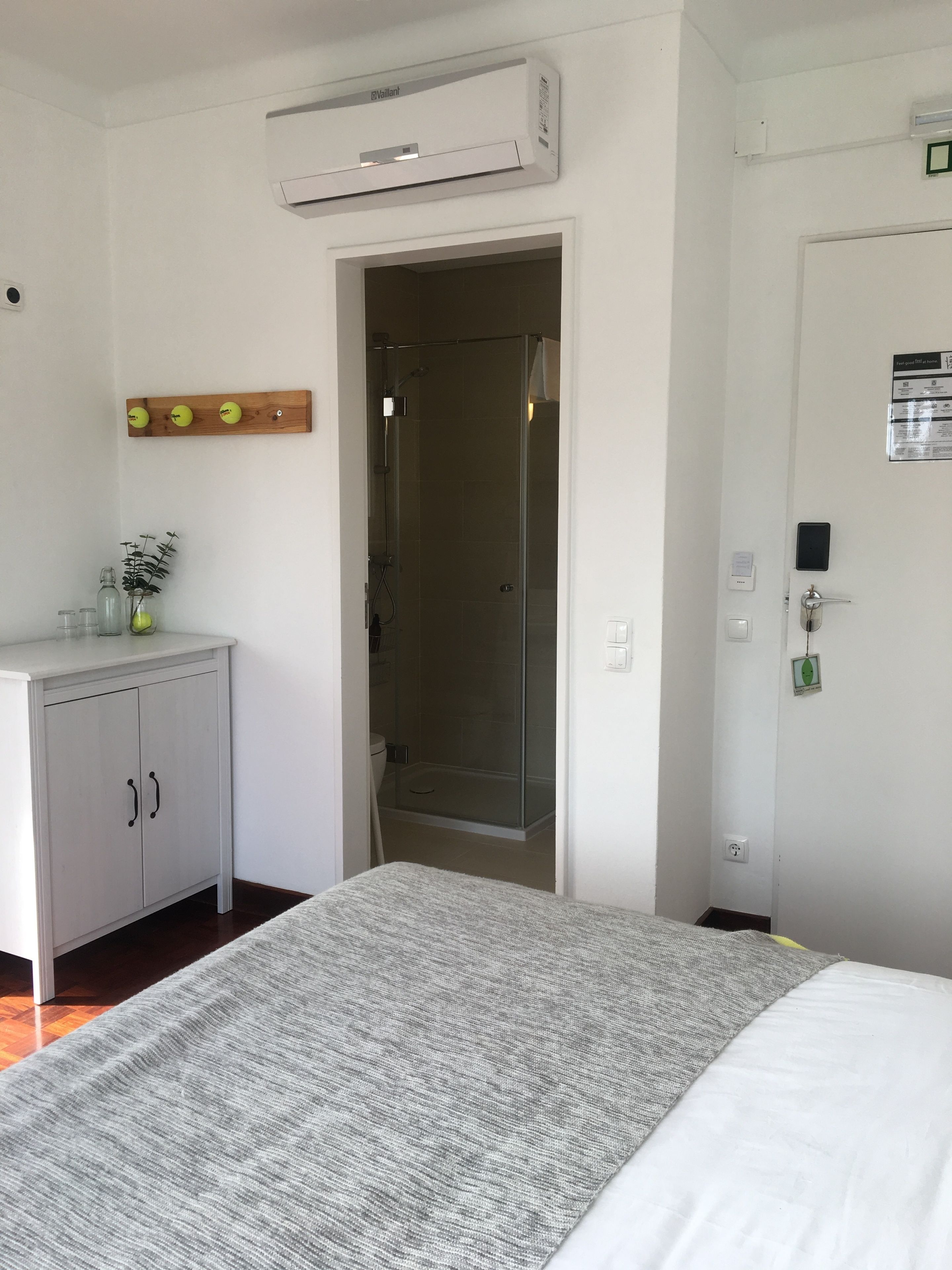 Une chambre d’hôtel équipée d’un lit, d’une armoire, d’un espace douche et d’un climatiseur fixé au mur.