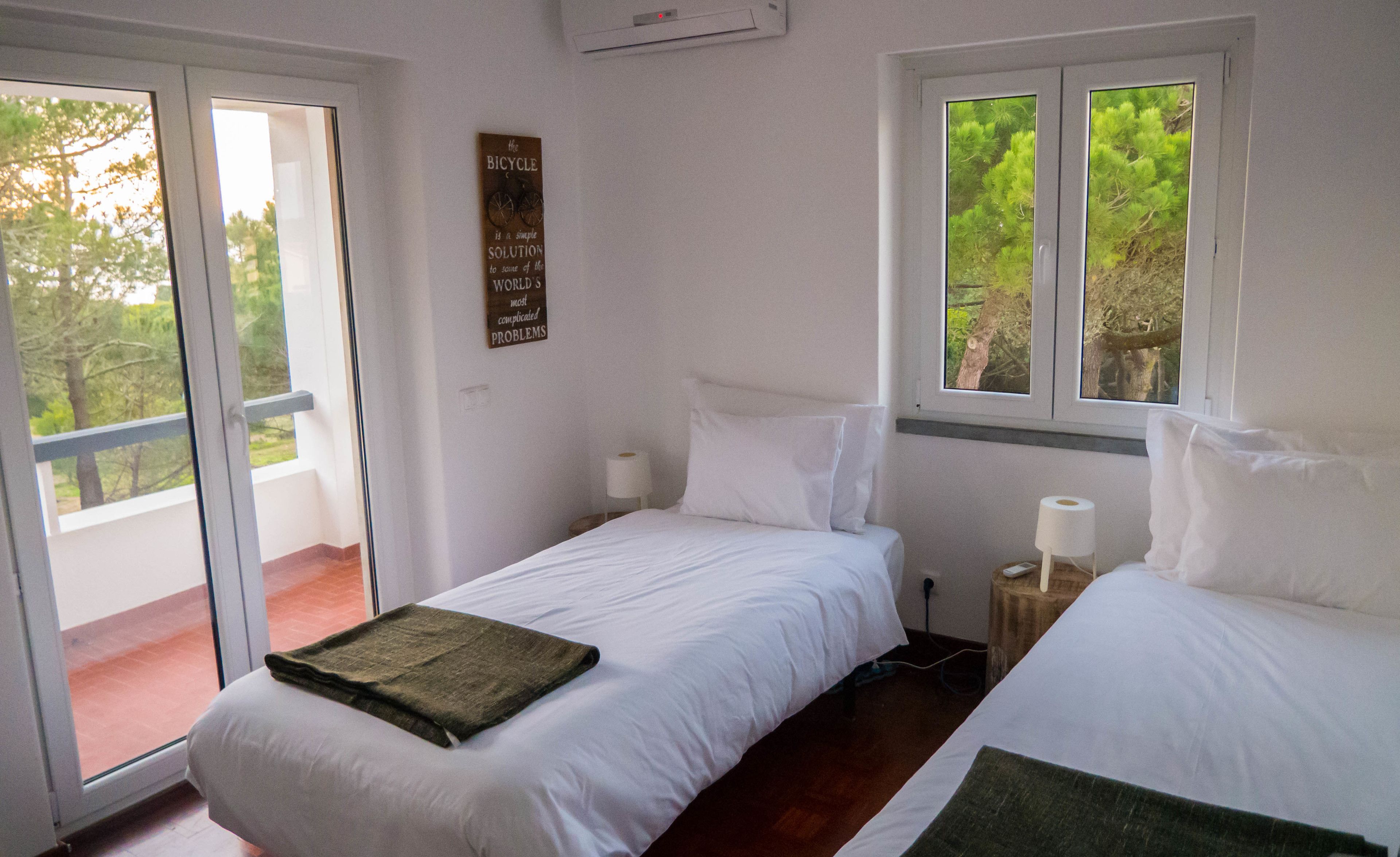 Un dormitorio con dos camas, una ventana con vistas a árboles y un cartel en la pared.