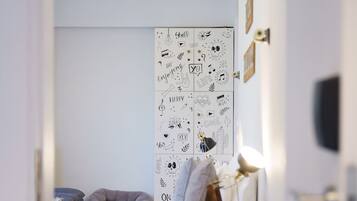 A bedroom with a bed, a wooden ladder, and a wall with various doodles.