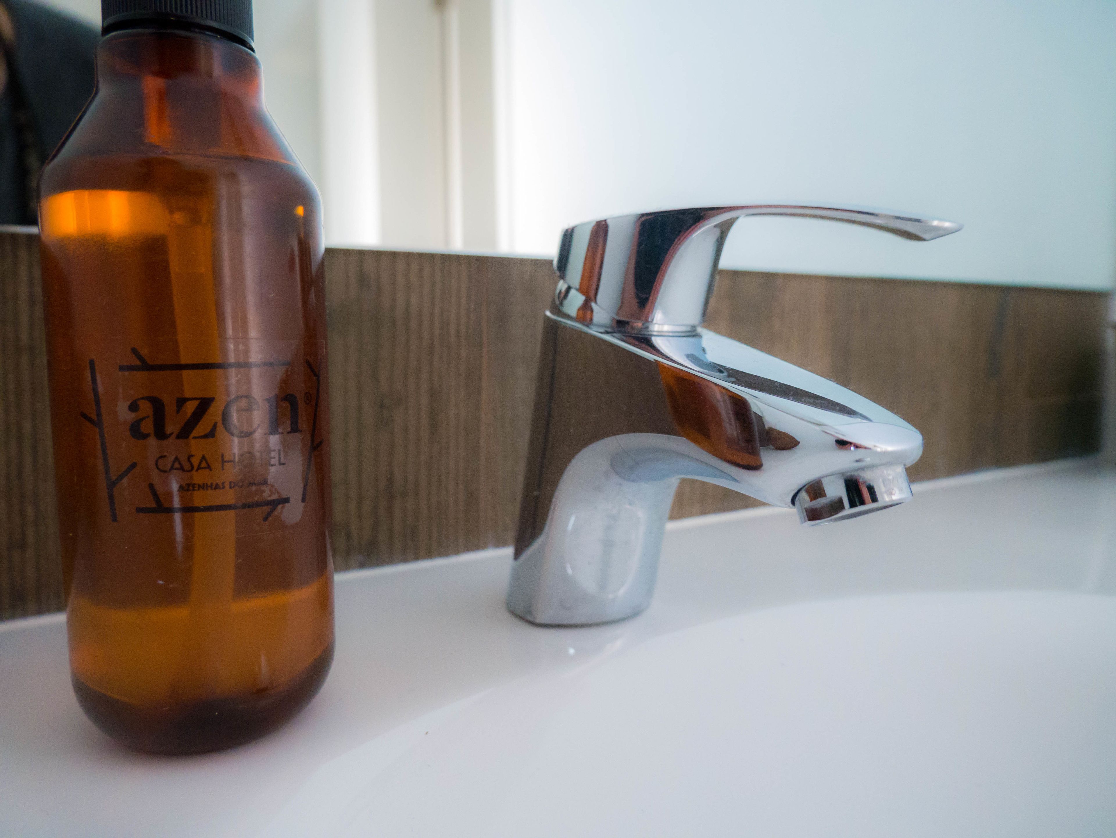 Une salle de bain avec une bouteille de « Azenha » et un robinet moderne.