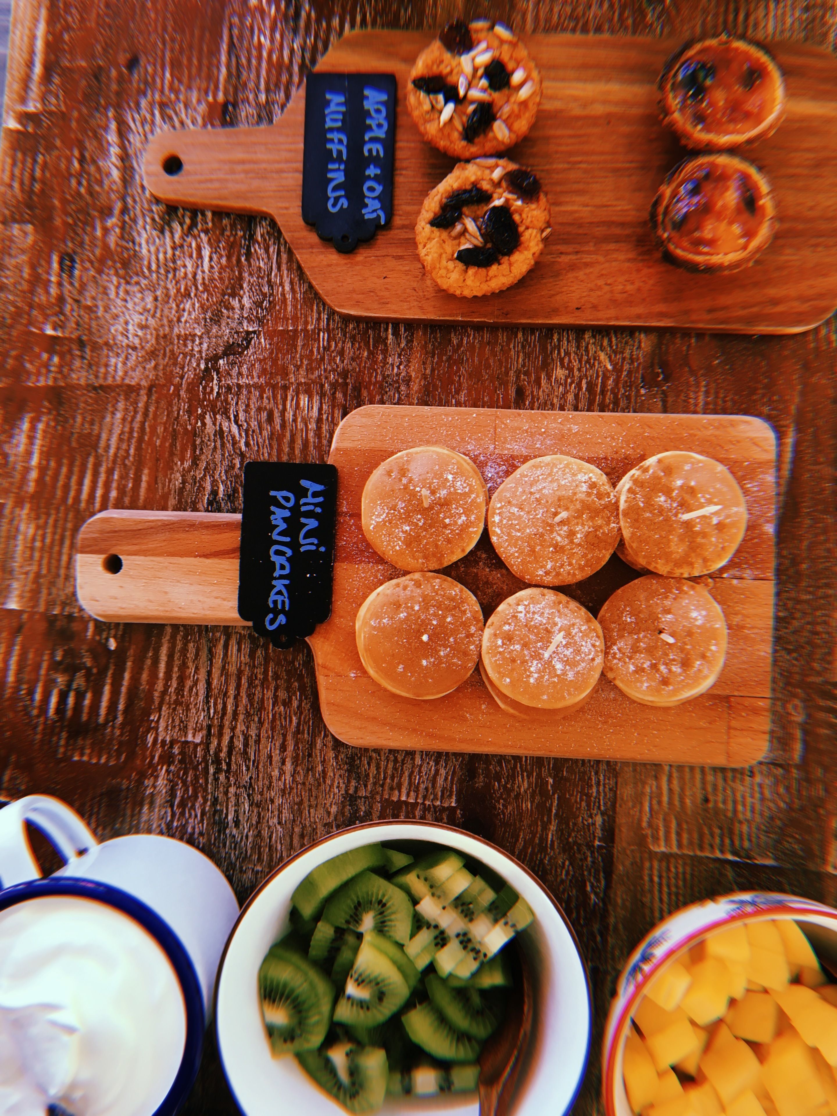 Ein Holztisch mit verschiedenen Speisen, darunter Muffins und Obst.