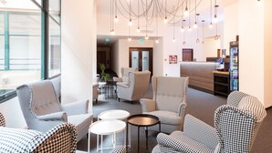 A modern lobby with houndstooth patterned chairs, a coffee machine, and a reception desk. - Narodni Stay (Prague)