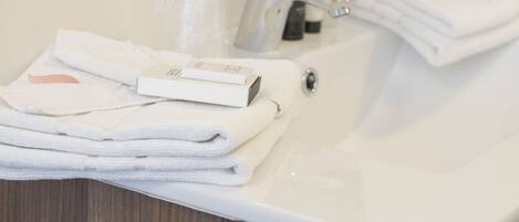 A bathroom sink with neatly stacked white towels and a soap dispenser.