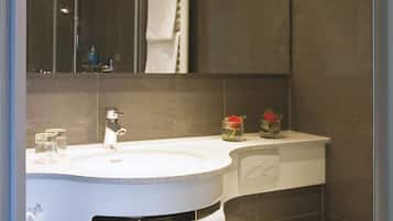 A modern bathroom with a round mirror, a white sink, a toilet, and a towel rack.