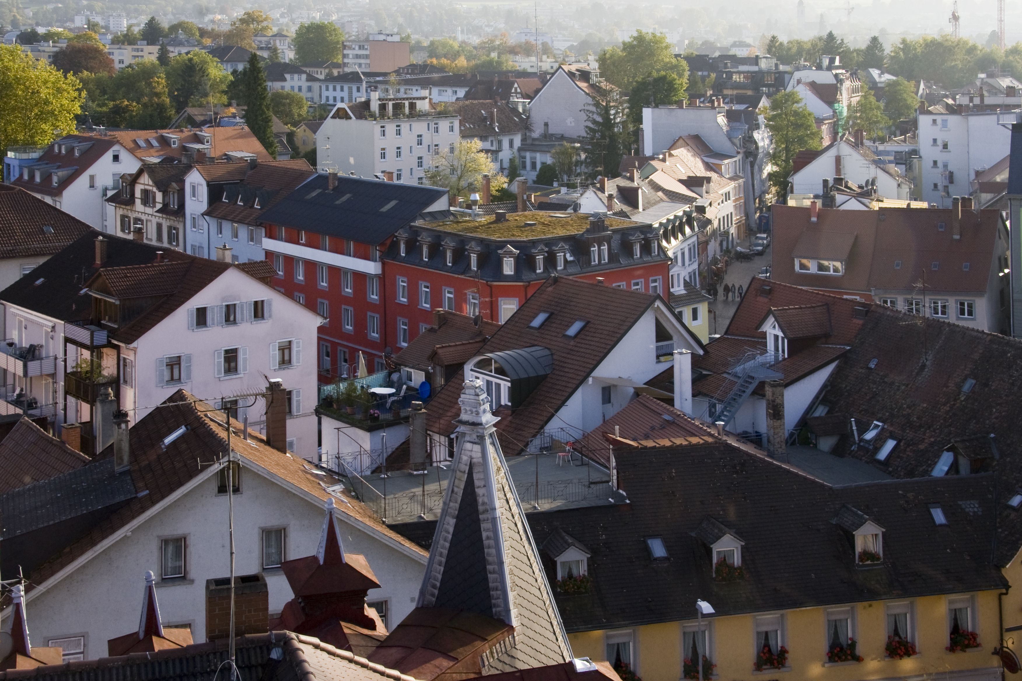 A densely packed urban area with various buildings, including a prominent red building with a unique roof structure.