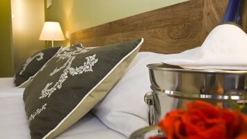 A neatly made bed with decorative pillows, a metal container, and a red rose.