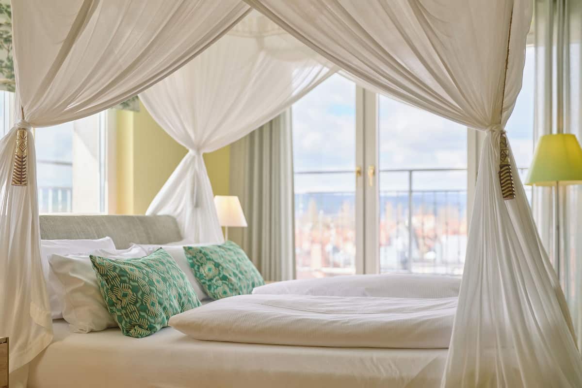 A bed with white bedding, green patterned pillows, and a canopy.