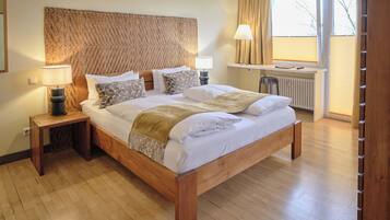 A wooden bed with a woven headboard, bedside lamps, and a window with curtains.
