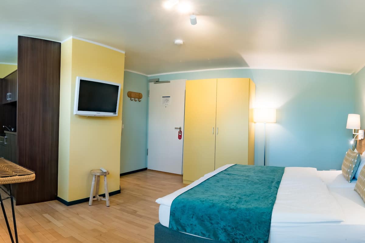 A hotel room with a bed, a TV, a dining table, and a chair.