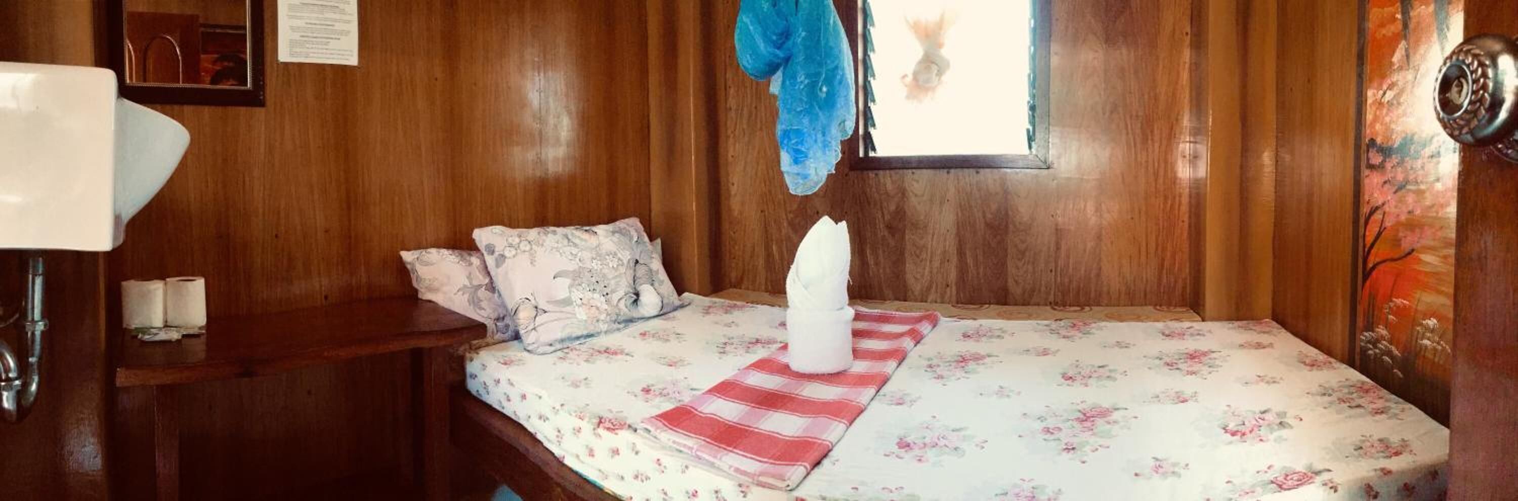 Une pièce en bois avec un lit, une table de chevet, une fenêtre donnant sur un beau paysage et une porte ornée d’un tableau.