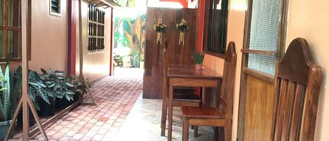 A narrow hallway with a tiled floor, wooden furniture, and potted plants.