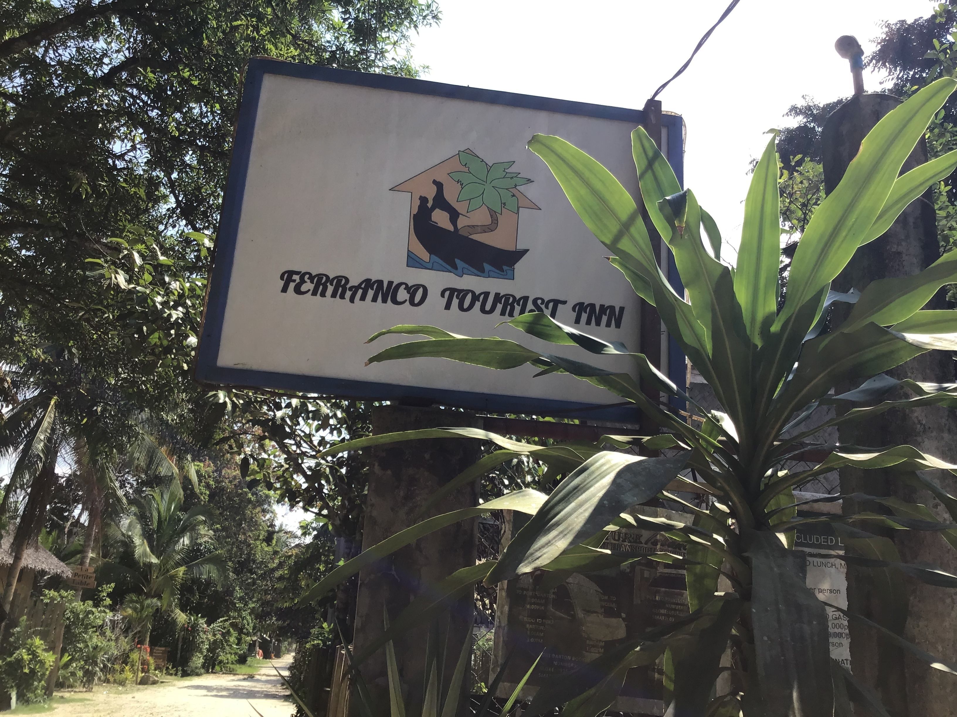 A sign for Ferranco Tourist Inn with a logo of a house and a palm tree.