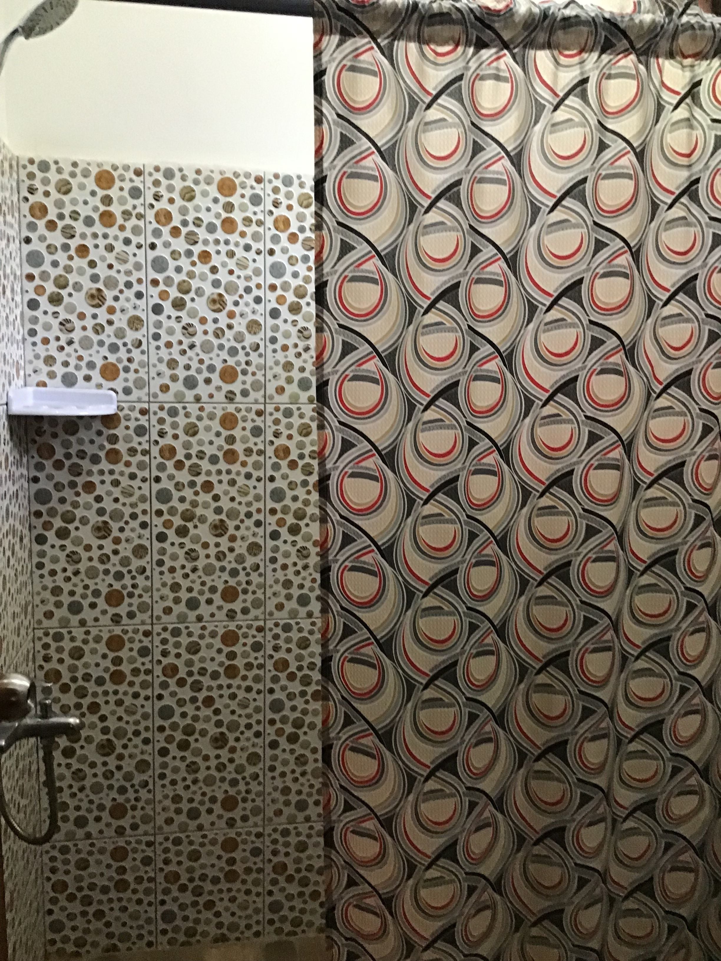 A bathroom with a polka dot tile wall and a patterned shower curtain.