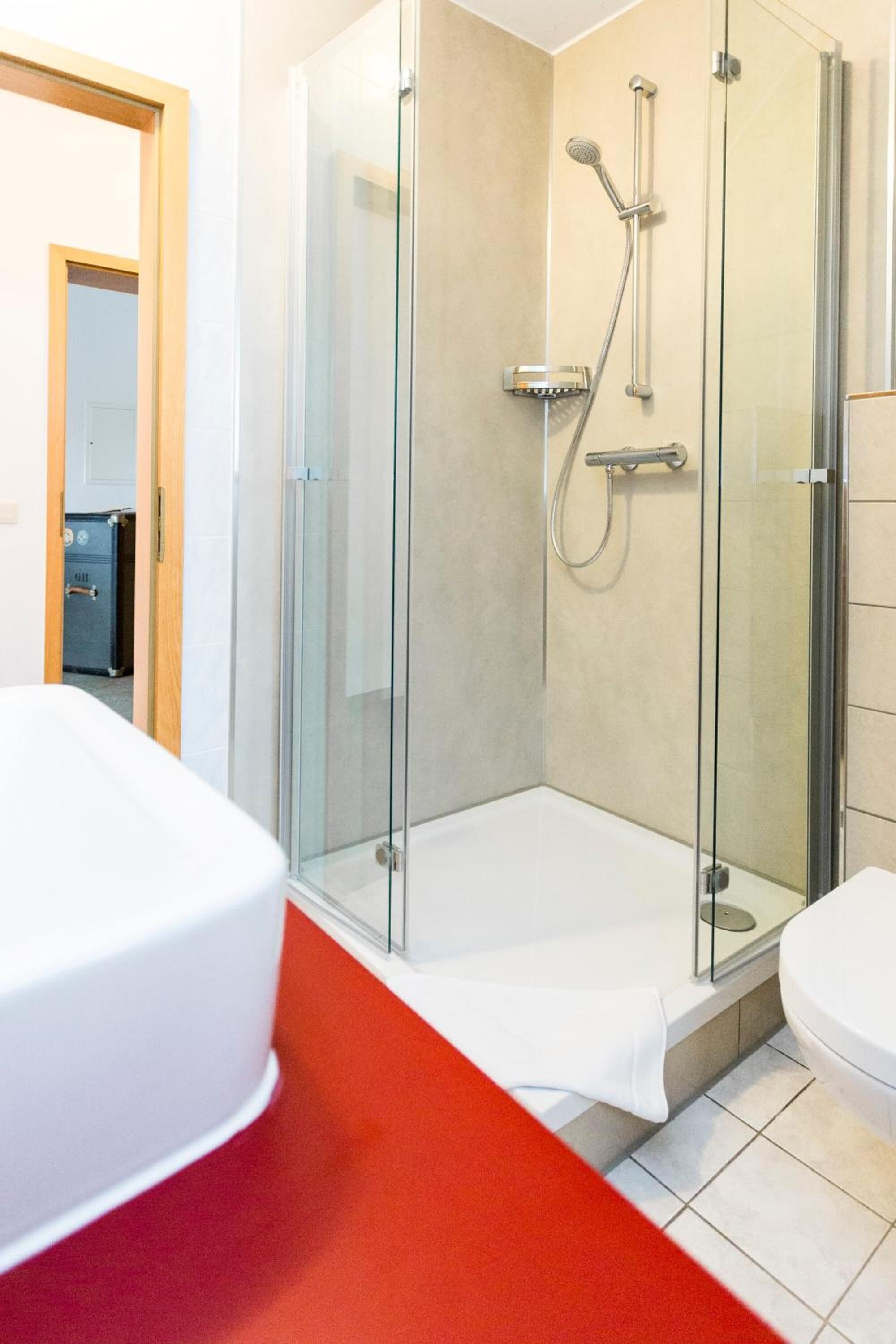 Ein modernes Badezimmer mit einer gläsernen Duschkabine, einer weißen Badewanne und einer Toilette.