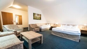 A hotel room with a large bed, two armchairs, a small table, and a mirror on the wall. - Pension & Restaurant Nordstern (Cottbus)