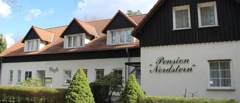 A two-story building with a sign reading "Pension Nordstern."