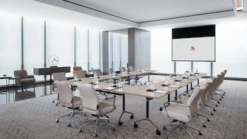 A modern conference room with a long table, chairs, and a presentation screen.