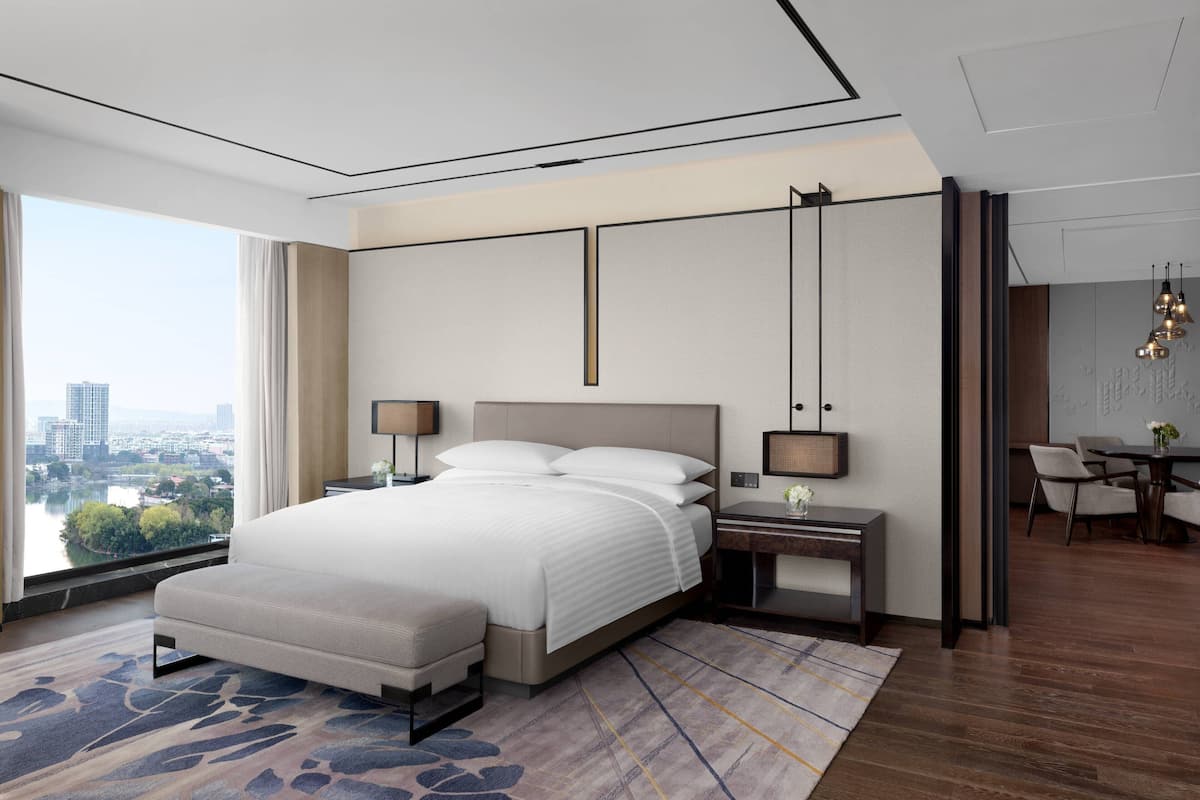 Ein modernes Hotelzimmer mit einem großen Bett, Nachttischen, einem Schreibtisch und Blick auf die Stadt.