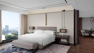 A modern hotel room with a large bed, bedside tables, a desk, and a view of the city.
