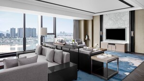 Une chambre d’hôtel moderne dotée d’une grande fenêtre, d’un téléviseur à écran plat, d’un canapé, d’une table basse et d’une petite table d’appoint.