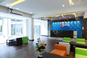 A modern lobby with a reception desk, comfortable seating, and a large window providing natural light. - 2Bedtel (Bangkok)