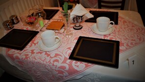 A table set with a white tablecloth, a rose, a vase, a teapot, a cup, a saucer, a tray, and a book. - The Woodland Hotel (Blackpool)