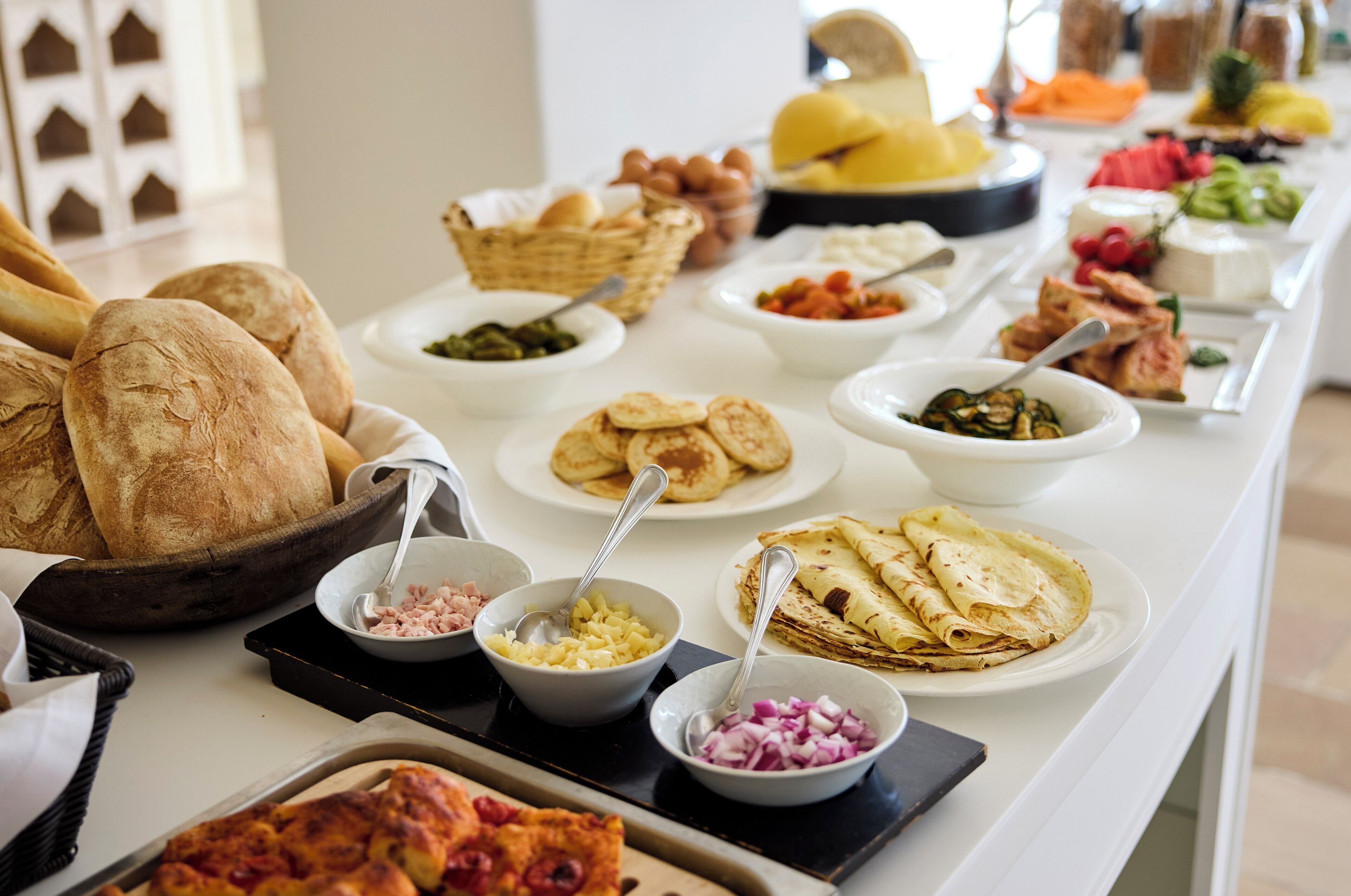Une table de buffet proposant divers aliments, notamment du pain, du fromage et des légumes.