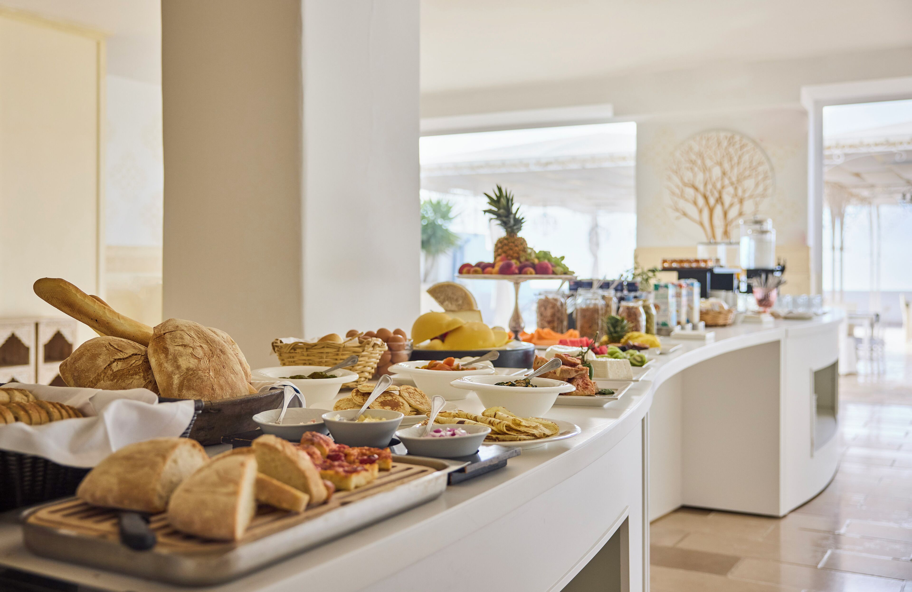 A buffet with various food items including bread, fruits, and pastries.