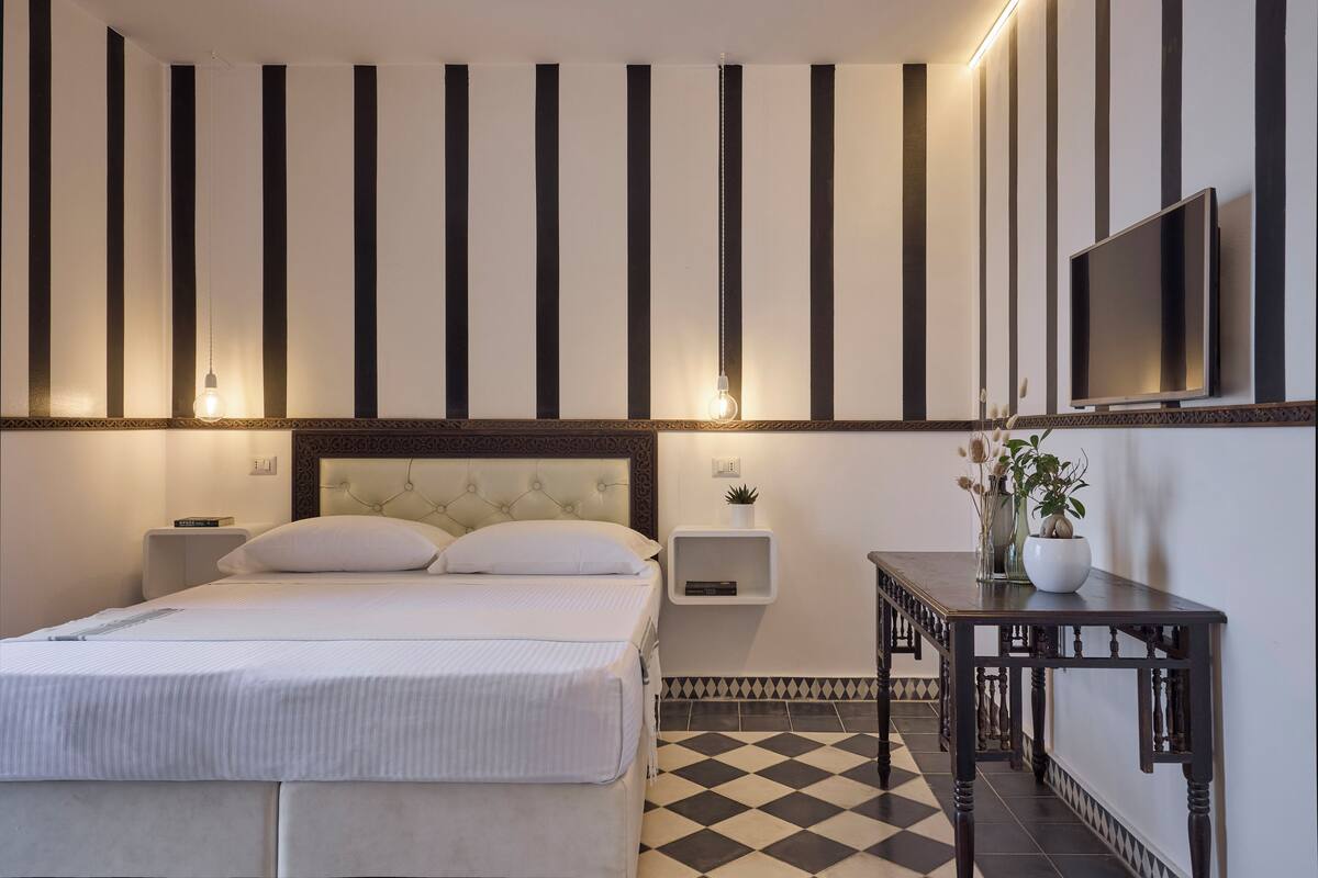 Ein Hotelzimmer mit Bett, Nachttischen, einem Fernseher und einem Schachbrettmuster-Boden.