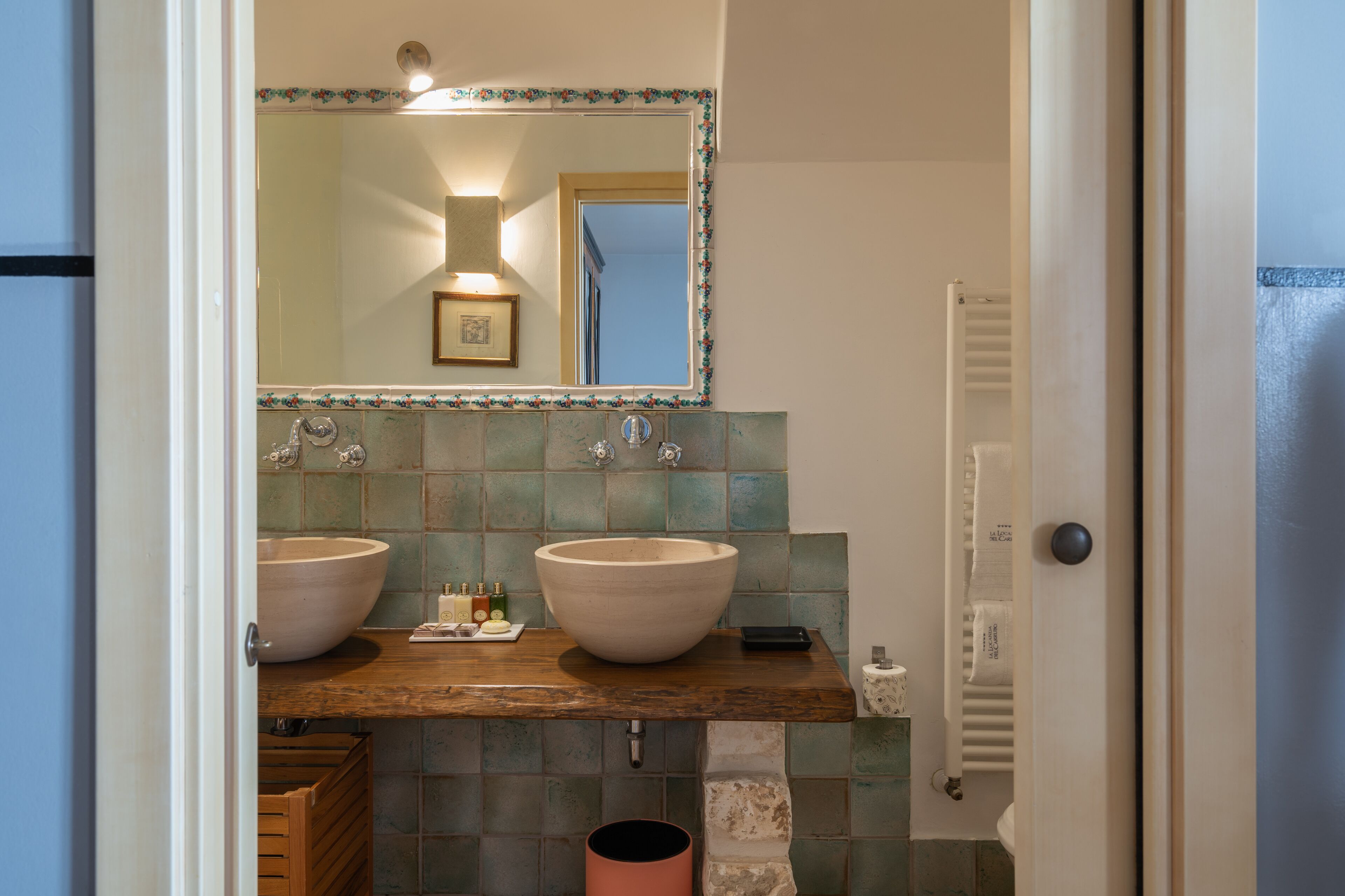 Een badkamer met twee wasbakken, een spiegel en een betegelde spatwand.