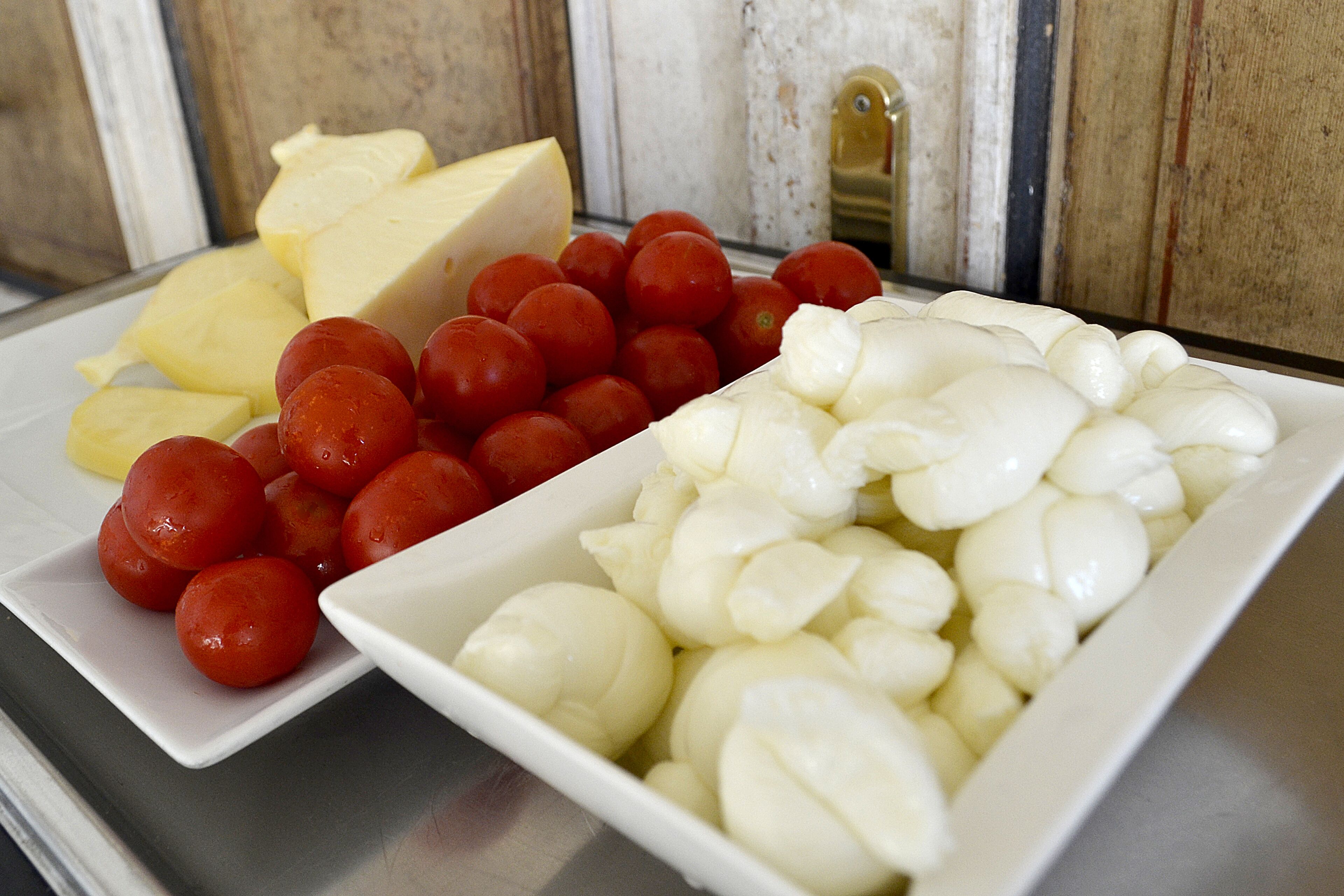 Um prato branco com queijo, tomate e bolinhas de mussarela.