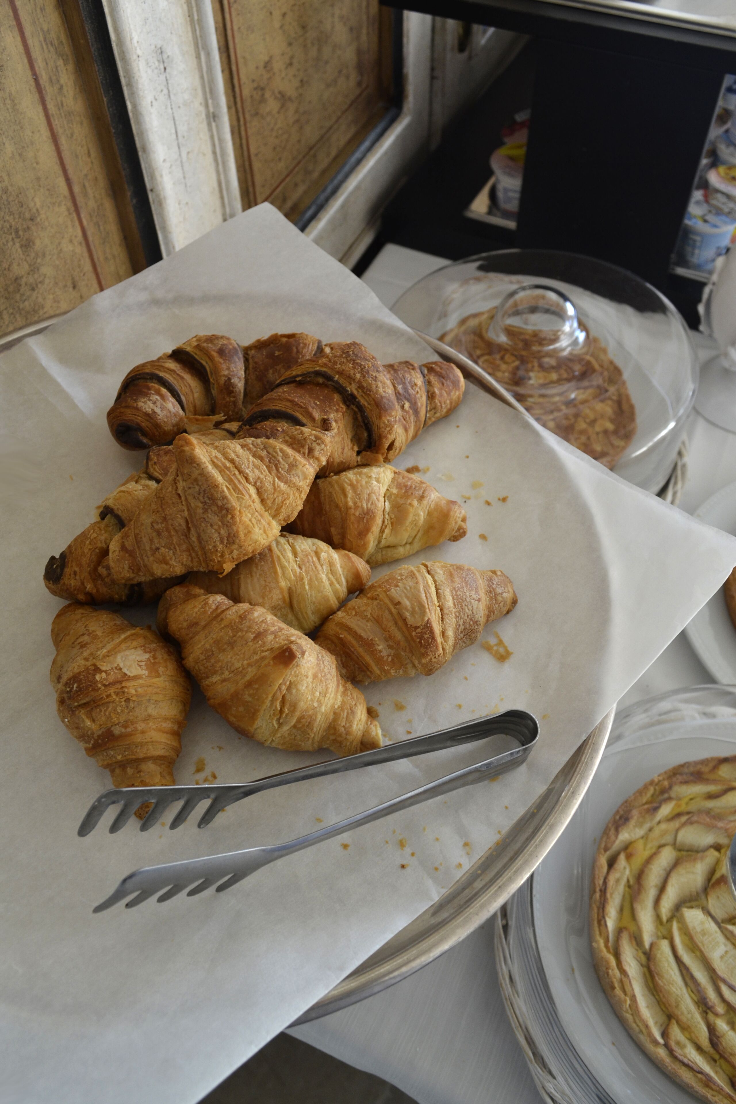 A plate of croissants and a pie on a table.