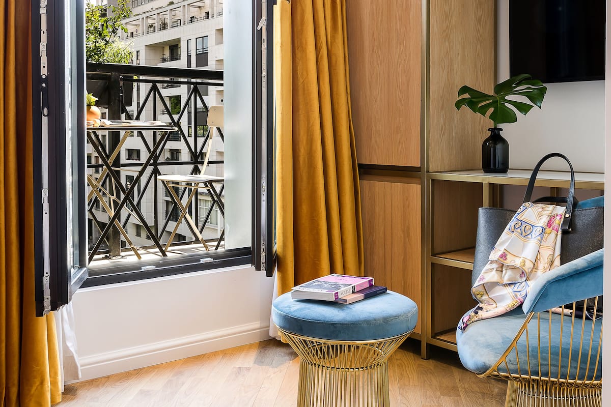 Una habitación con balcón, un sofá, una mesita y un televisor.