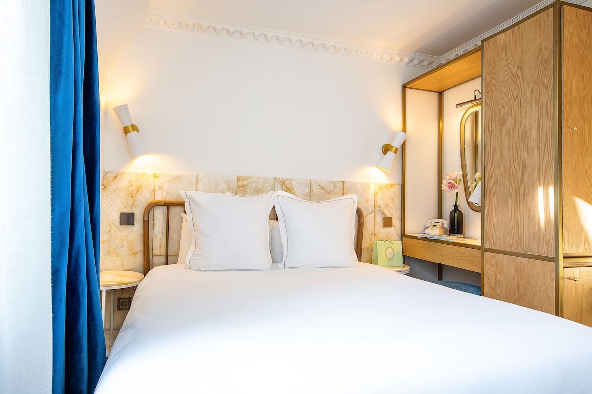Una habitación de hotel con cama, mesita de noche, espejo y armario.