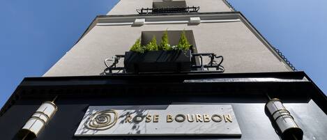 Un edificio con un letrero que dice "ROSE BOURBON" y un balcón con plantas.
