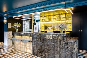 Un espace d’accueil doté d’un comptoir en marbre, de tabourets de bar et d’un intérieur bien éclairé.