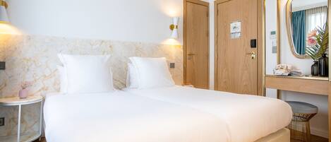 A neatly made bed with white linens, a wooden headboard, and a bedside table with a lamp.