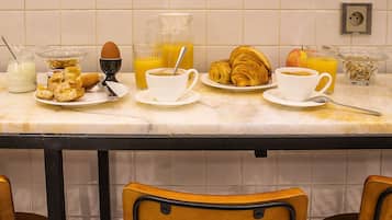 A breakfast setup with croissants, eggs, and orange juice on a marble countertop.