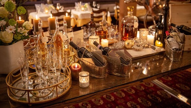 A well-lit dining area with a table set for a meal, featuring a variety of glassware, bottles, and candles. - Hotel Wittelsbacher Hof (Oberstdorf)