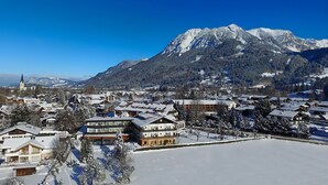 A snow-covered town with traditional wooden houses and a church, surrounded by mountains. - Hotel Wittelsbacher Hof (Oberstdorf)