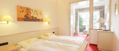 A hotel room with a bed, bedside lamps, a painting, and a window with a view.