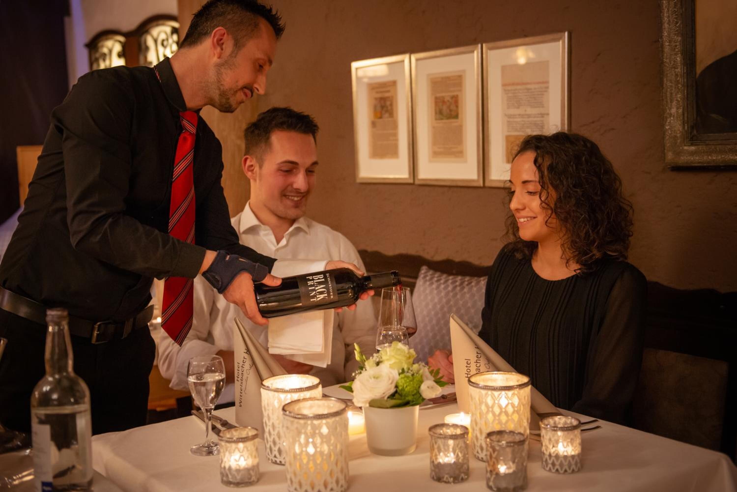 A hotel dining area with a table set for three, candles, and a menu.