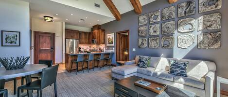 A modern living room with a sofa, coffee table, and dining area.