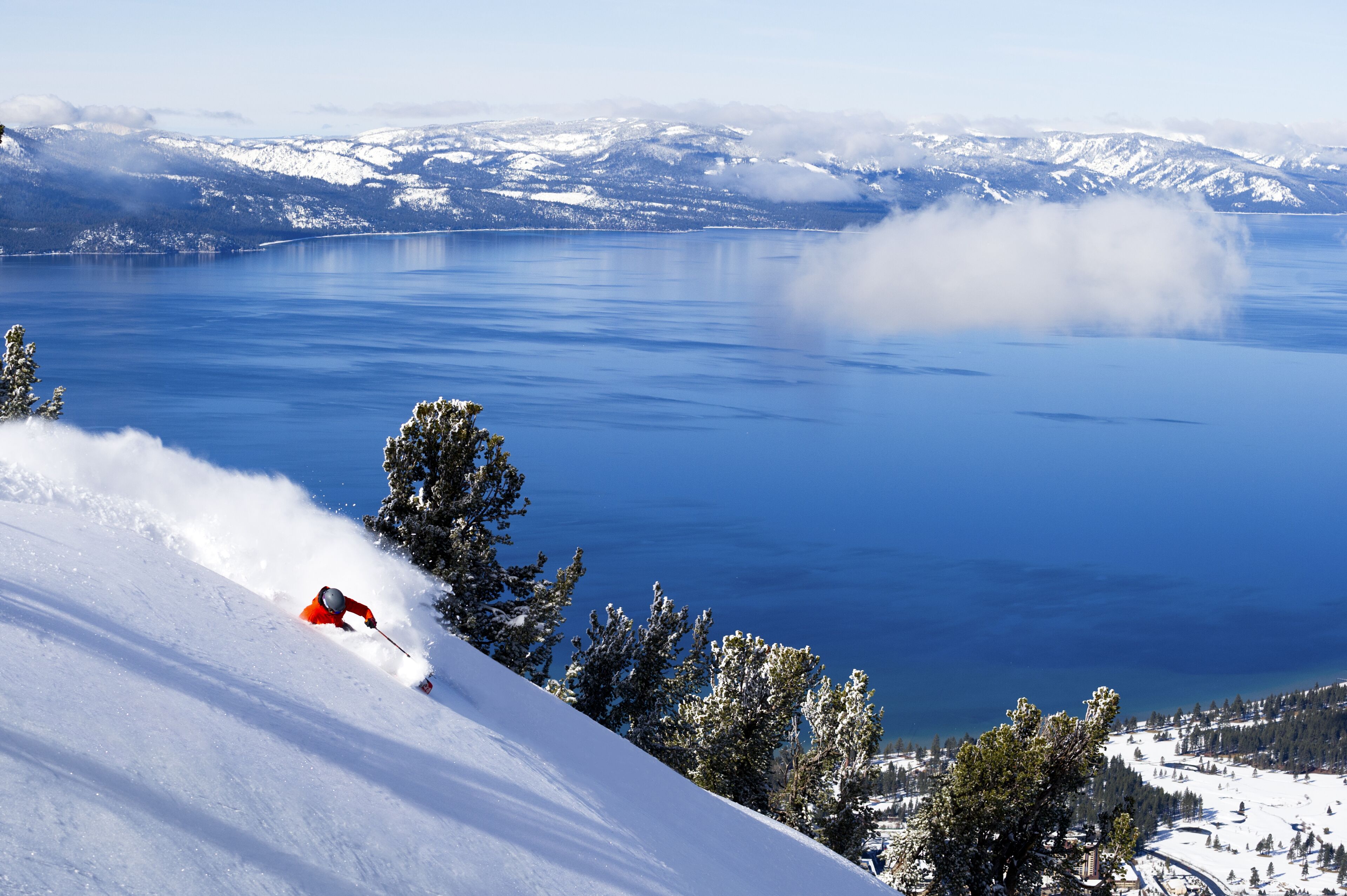 A snowy mountain slope with a skier in red gear.