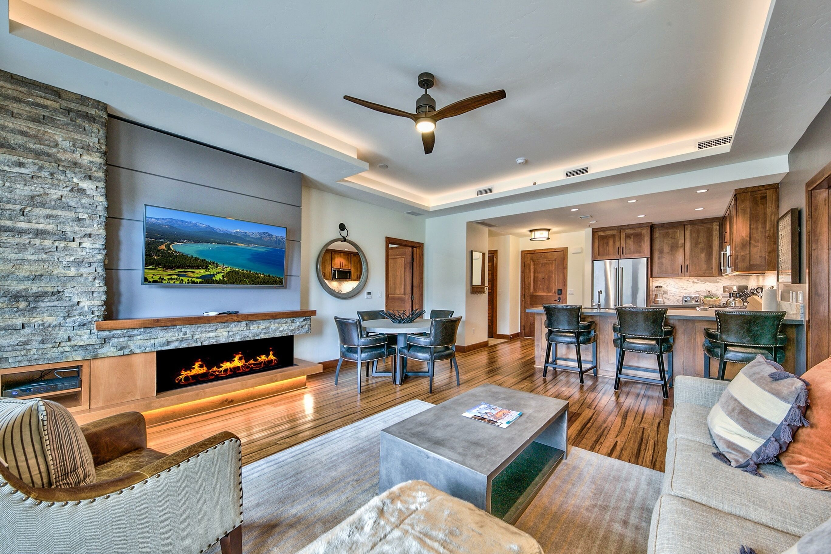 A spacious living area with a fireplace, a large flat-screen TV, and a stone accent wall.